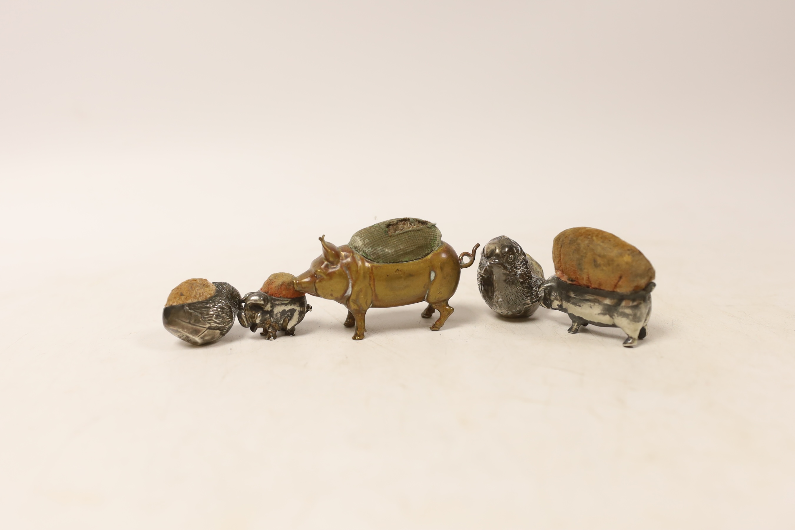 Two Edwardian silver mounted novelty pin cushions, modelled as hatching chicks, both by Sampson Mordan & Co, 1907 & 1909, largest height 33mm, together with three base metal mounted pin cushions.